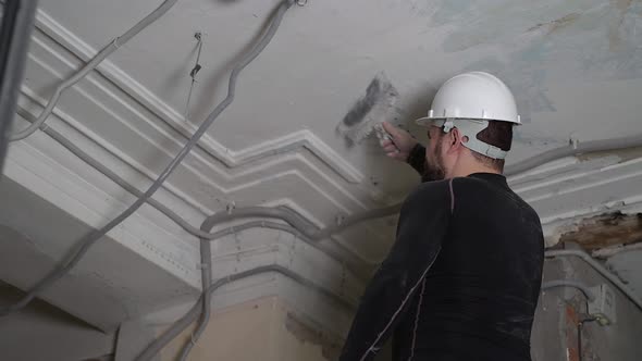 Fat Bearded Adult Man in Protective Helmet and Black Tight Fitting Clothing Remove Construction