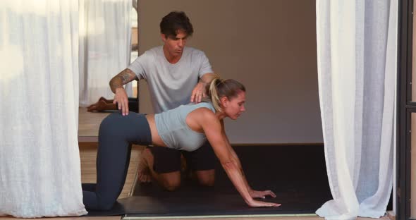 Trainer supporting woman doing plank exercise