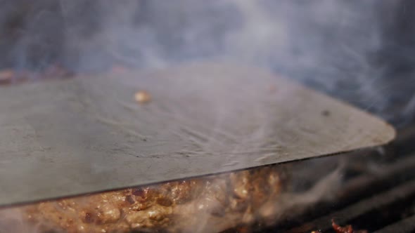 Slow motion of beef hamburger on a grill in close up with flames and smoke