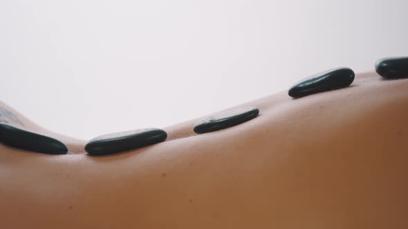 Hot Stone Massage on the Back of a Naked Woman