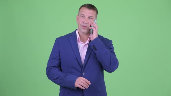 Mature Macho Businessman in Suit Showing Stop Gesture While Talking on the Phone