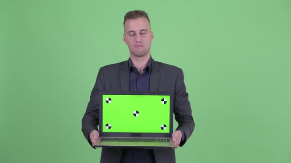 Stressed Businessman in Suit Showing Laptop