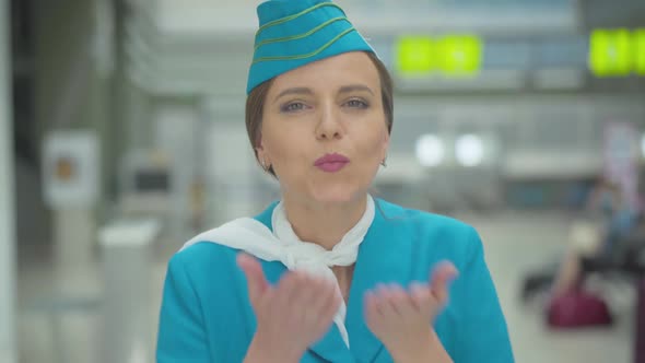 Smiling Beautiful Caucasian Stewardess Sending Air Kiss at Camera. Portrait of Charming Mid-adult