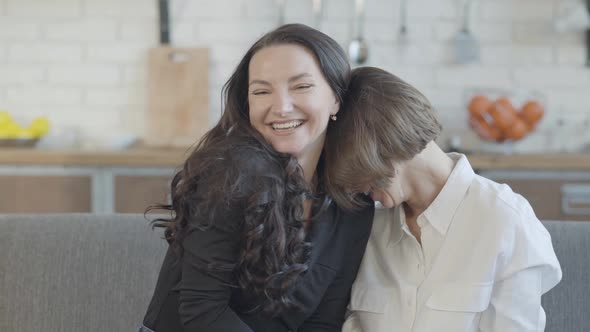 Two Happy Young Caucasian Women Laughing Sitting on Couch at Home