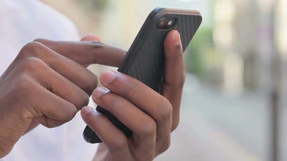 Close Up of Hands of African Man Using Smartphone