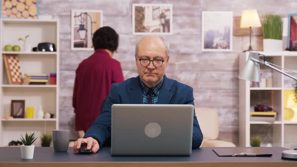 Handsome Old Man Taking a Sip of Coffee While Working on Laptop