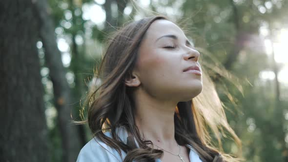 Close Up Portrait of Young Brunette Girl Smiling and Enjoying Fresh Breeze. Slow Motion. Woman with