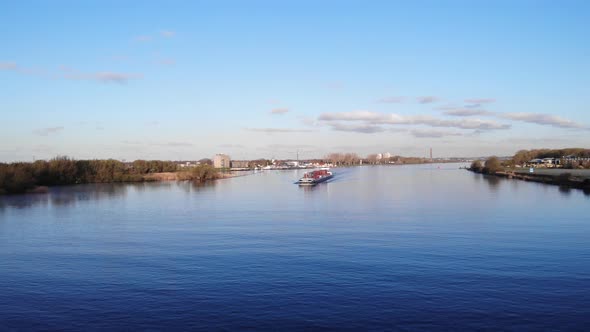 Barge With Cargos Sailing At Oude Maas River Passing By Zwijndrecht Town In Netherlands. - aerial