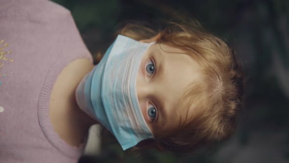 Little Girl in a Medical Mask. Vertical Video