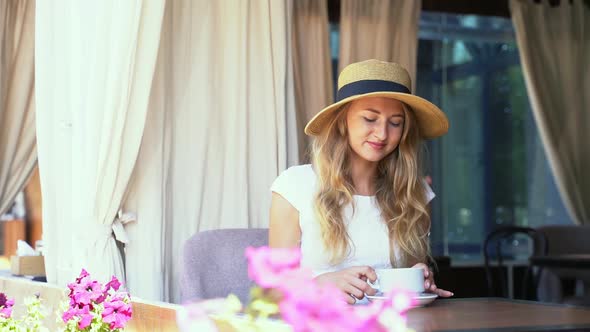 Young Woman Drinking Coffee at Street Cafe