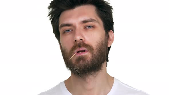 Young Bearded Man with a Toothpick in Mouth Acting Loose on White Background