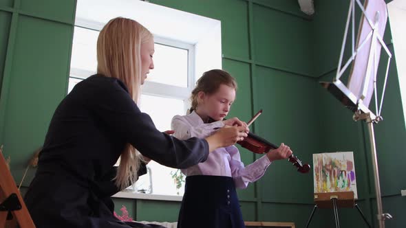 Violin Lesson  a Little Girl Playing Violin in the Class and Her Teacher Sitting Next to Her