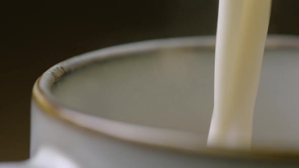 ZOOM IN frothy milk is poured into a cup to make a cappuccino, 60fps