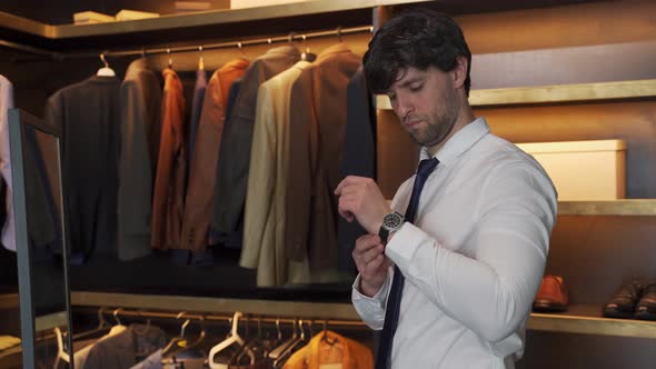 Man in a Shirt Buttons Up His Wristwatch in the Dressing Room
