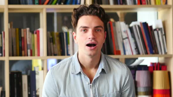 Amazed Happy Young Man in Library Surprise