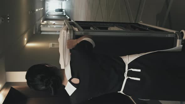 Female Housekeeper Carrying Hand Cart along Hotel