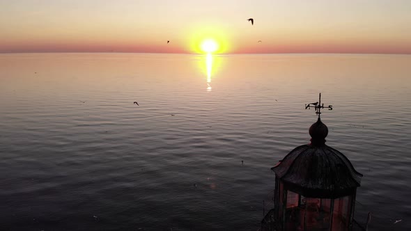 Sunset at large lake, aerial camera fly back and show old lighthouse at isle