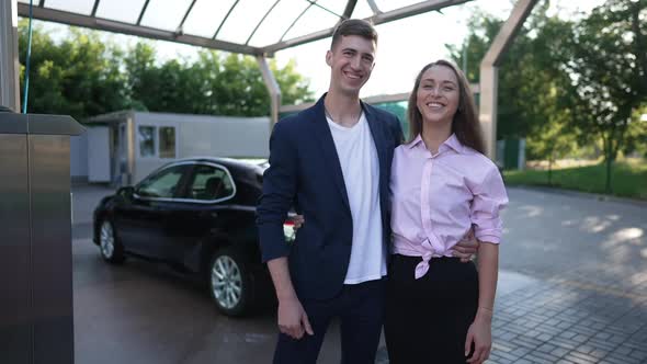 Satisfied Caucasian Couple Gesturing Thumbs Up Smiling Looking at Camera Posing at Car Wash Station