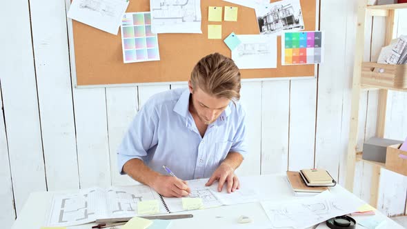 Young Successful Architector Checking Drawings Sitting at Workplace