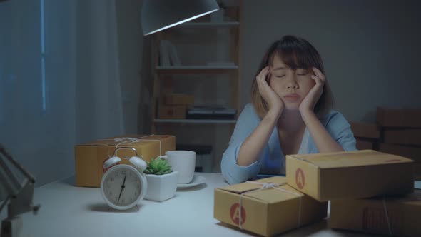 Young Asian business woman owner of SME sleepy exhausted working at office desk in night at home.