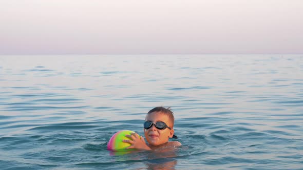 Happy Child Bathing in the Sea with Ball