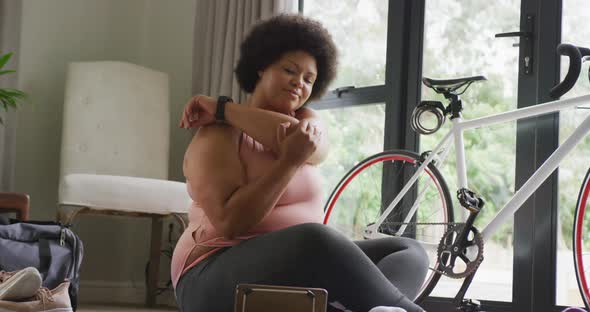 Video of midsection of plus size african american woman in sport clothes stretching at home
