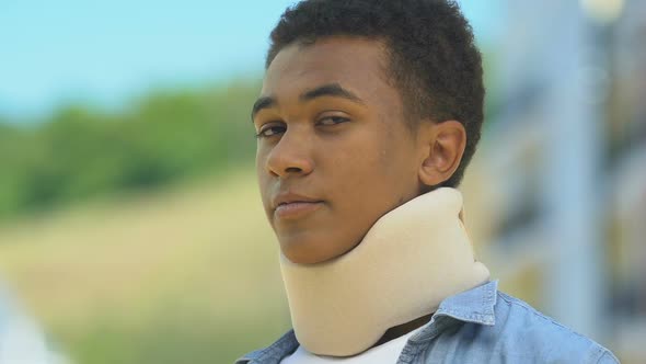 Afro-American Boy In Foam Cervical Collar Looking Upset Outdoors