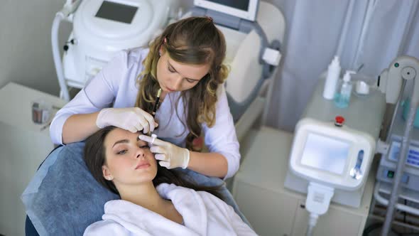 Beautician Doing Permanent Makeup for Eyebrows in Beauty Salon