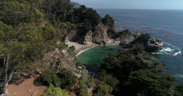 Aerial shot flying over trees to reveal Water Fall McWay Falls Julia Pfeiffer Burns Park Big Sur Cal