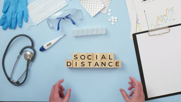 On medical table put hands wooden cubes with the phrase social distance, the view from above.