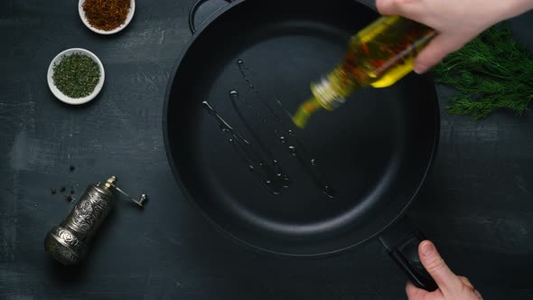 Man Pouring Cooking Oil on the Frying Pan  Top View on a Dark Background