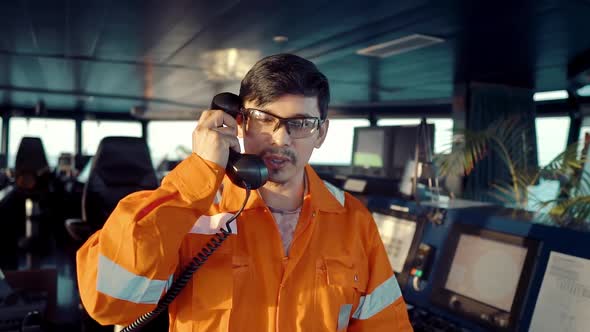 Filipino Deck Officer on Bridge of Vessel or Ship. He Is Speaking on GMDSS VHF Radio