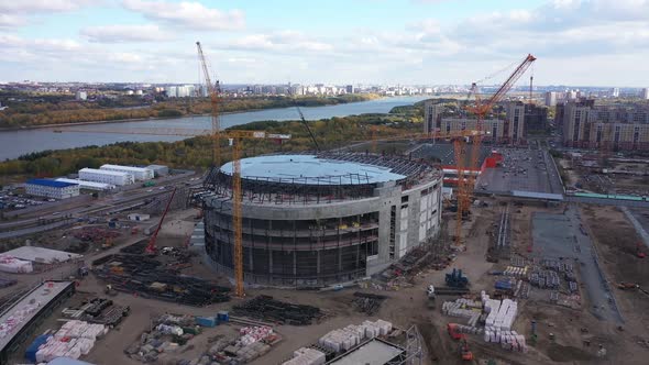 Large Sports Stadium Building and Tower Cranes on River Bank