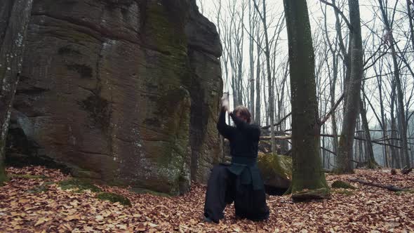 Man in Traditional Japanese Clothes, with a Sword, a Katana, Trains Martial Arts in the Forest