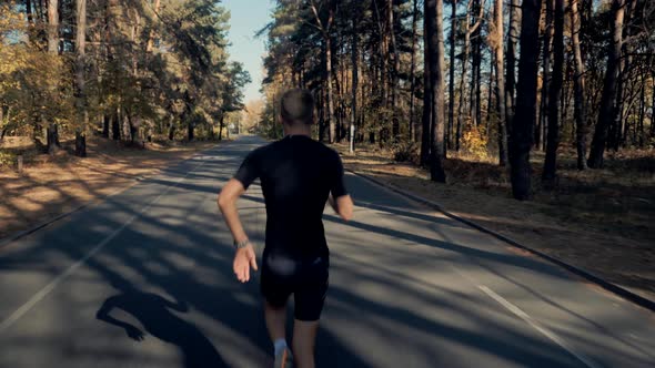 Running Man In Forest At Sunset. Runner Man Fit Athlete Legs Jogging On Trail Ready To Triathlon.