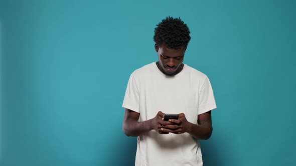 African American Man Feeling Excited and Using Smartphone