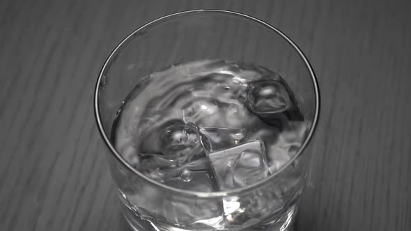 Slow motion of falling ice cube into water with splashes