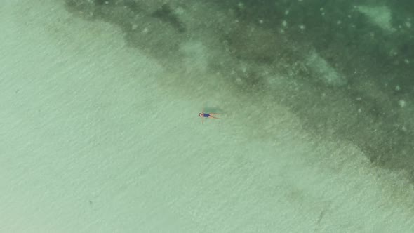 Aerial top down: Woman swimming in turquoise water tropical sea Pasir Panjang Ke