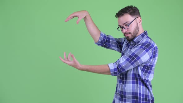 Happy Young Bearded Hipster Man Snapping Fingers and Showing Something