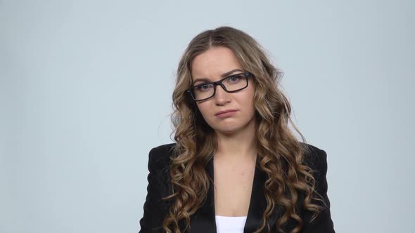 Female Disappointed Looks in Camera and Shrugs Then Waving His Head No Against Grey Background, Slow