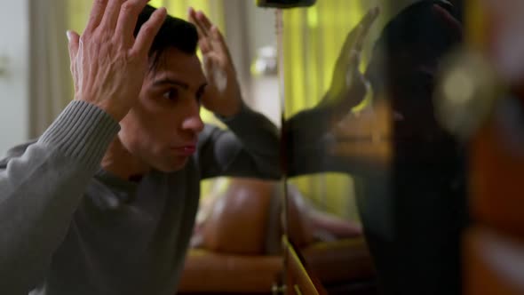 Shocked Young Man Holding Head in Hands Looking Inside Oven in Kitchen at Home