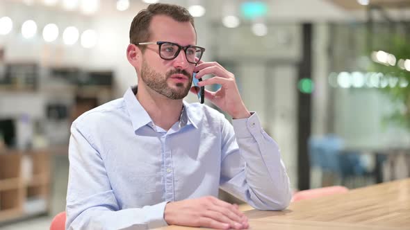 Cheerful Businessman Talking on Smartphone in Office