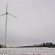 Low angle shot of rotating wind turbines on a snowy field in Germany. Wide shot of a wind farm. - VideoHive Item for Sale