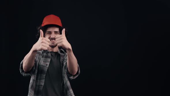 The Portrait of an Optimistic Hipster with a Red Cap Pointing with His Index Finger to One Side Then