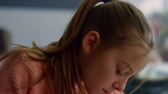 Girl Drawing in Notebook at Desk in Classroom