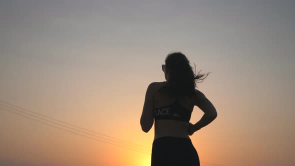 Active Slim Girl Jogging on Country Road with Evening Sky at Background. Unrecognizable Female