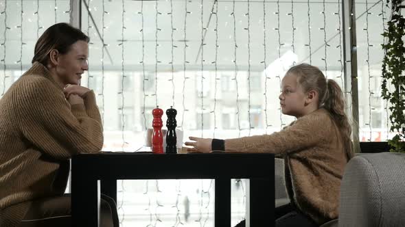 Mother and Daughter Sit in a Restaurant and Wait for Their Order