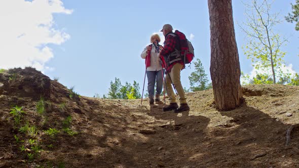 Elderly Man Helping Wife on Trekking Trip