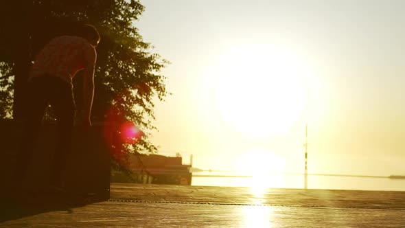 Silhouette of Young Caucasian Male Riding Skateboard and Doing Kickflip Trick