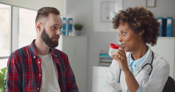 Black Female Physician Prescribing Pills to Young Male Patient